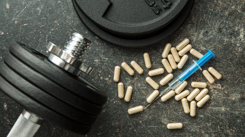 Doping in sport. Syringe and dumbbell.